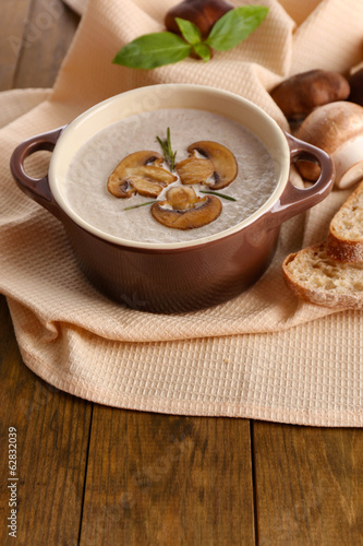 Photo: Mushroom soup in pot, on wooden background Mushroom soup in pot, on wooden background