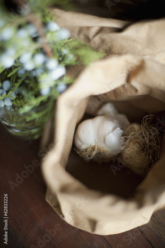 Photo: Organic ingredients on a table. Garlic bulbs in a brown paper bag. A herb with blue flowers. Fresh ingredients. Organic ingredients on a table. Garlic bulbs in a brown paper bag. A herb with blue flowers. Fresh ingredients.