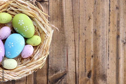 Photo: Easter eggs in nest on color wooden background Easter eggs in nest on color wooden background