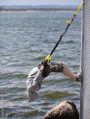 Photo: man outdoor,suspension training at the sea man outdoor,suspension training at the sea
