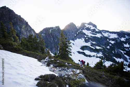 Photo: A young man hikes around a snow patch while going to the summit of a large mountain in the Cascades of Washington, USA. A young man hikes around a snow patch while going to the summit of a large mountain in the Cascades of Washington, USA.