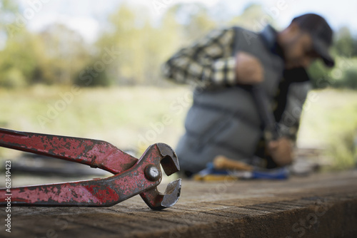 Foto: A reclaimed lumber workshop. A man preparing the timber by removing all the nails and studs. A reclaimed lumber workshop. A man preparing the timber by removing all the nails and studs.