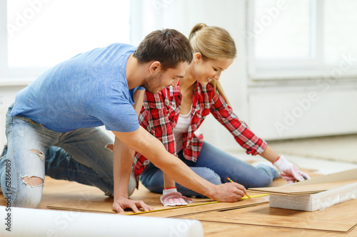 Photo: smiling couple measuring wood flooring smiling couple measuring wood flooring