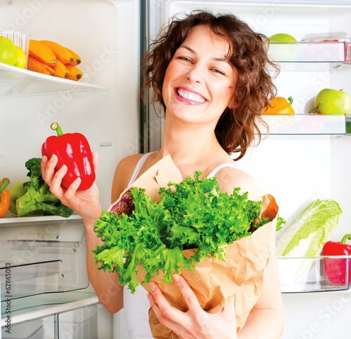 Photo: Beautiful young woman near the refrigerator with healthy food Beautiful young woman near the refrigerator with healthy food
