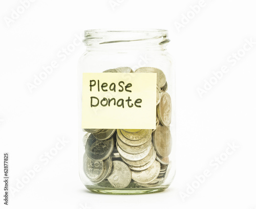 Photo: Isolated coins in jar with please donate label Isolated coins in jar with please donate label