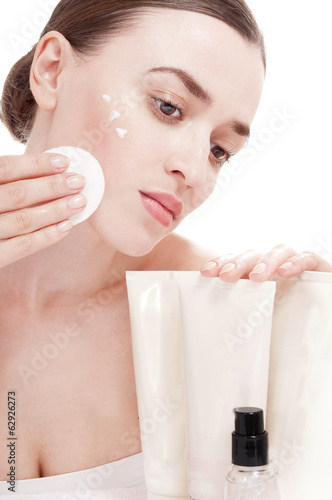 Photo: Woman with cotton swab near a tube of cream, isolated on white b Woman with cotton swab near a tube of cream, isolated on white b