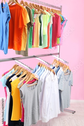 Photo: Different clothes on hangers, on pink background Different clothes on hangers, on pink background