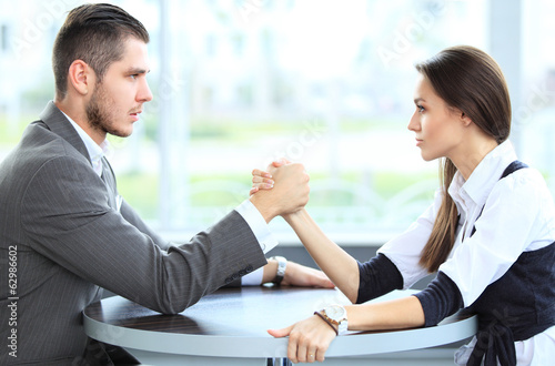Photo: businesswoman and businessman arm wrestling during meeting businesswoman and businessman arm wrestling during meeting