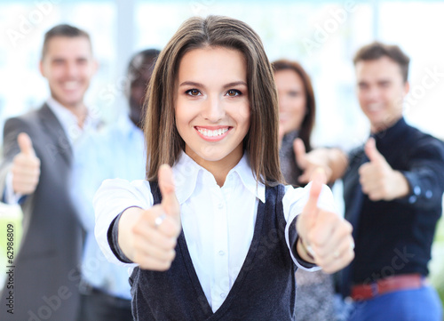 Photo: attractive businesswoman with team in office showing thumbs up attractive businesswoman with team in office showing thumbs up