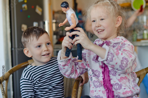 Photo: Happy little girl and boy playing with a doll Happy little girl and boy playing with a doll