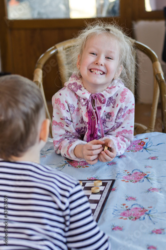 Photo: Beautiful laughing little girl playing checkers Beautiful laughing little girl playing checkers
