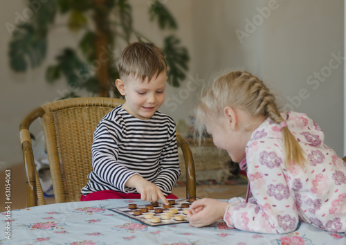 Photo: Young girl and boy playing checkers together Young girl and boy playing checkers together