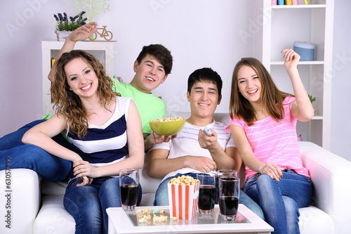 Photo: Group of young friends watching television at home Group of young friends watching television at home