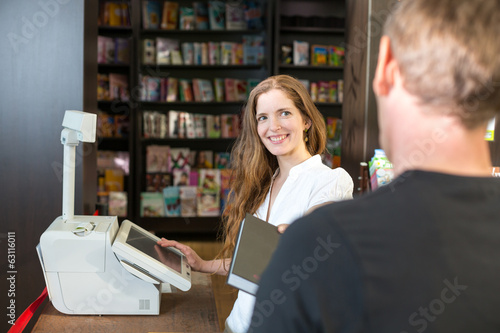 Photo: Cashier in bookstore serving a customer or client Cashier in bookstore serving a customer or client