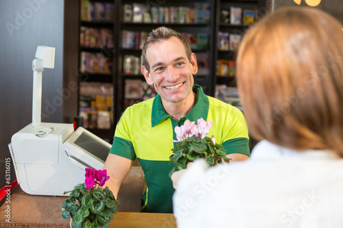 Photo: Cashier or shopkeeper in flower shop serving client Cashier or shopkeeper in flower shop serving client