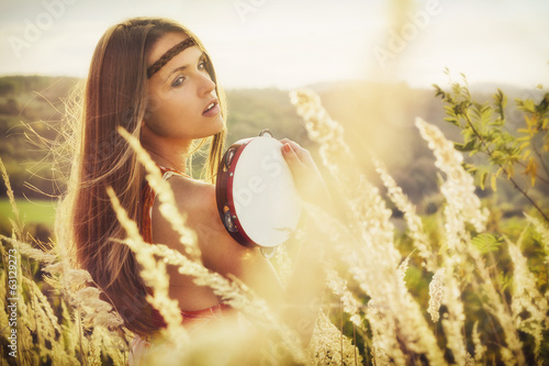 Photo: Beautiful young women playing in tambourine in autumn Beautiful young women playing in tambourine in autumn