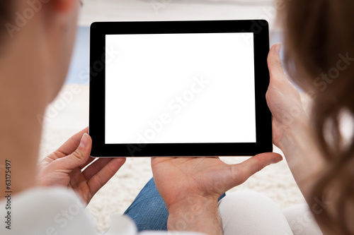 Photo: Young couple looking at a tablet together Young couple looking at a tablet together