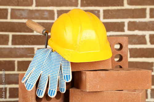 Photo: New bricks and building tools on brick wall background New bricks and building tools on brick wall background