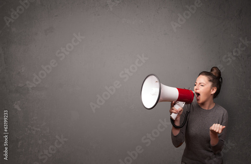 Photo: Girl shouting into megaphone on copy space background Girl shouting into megaphone on copy space background