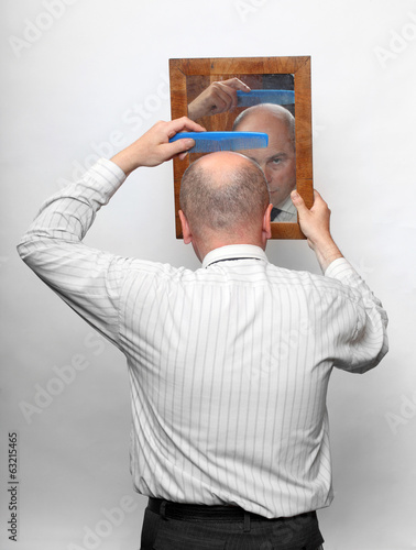 Photo: Funny picture of a man combing his hairless head. Funny picture of a man combing his hairless head.