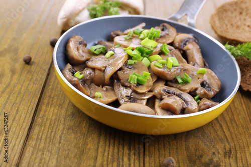 Photo: Delicious fried mushrooms in pan on table close-up Delicious fried mushrooms in pan on table close-up