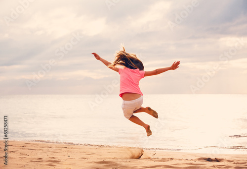 Photo: Happy Girl Jumping on the Beach at Sunset Happy Girl Jumping on the Beach at Sunset