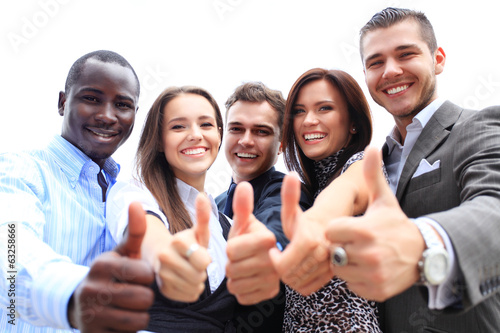 Photo: Successful young business people showing thumbs up sign Successful young business people showing thumbs up sign