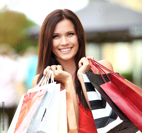 Photo: Beautiful woman holding shopping bags and smiling - outdoors Beautiful woman holding shopping bags and smiling - outdoors