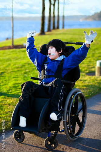 Photo: Disabled boy in wheelchair enjoying day at park Disabled boy in wheelchair enjoying day at park