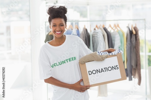 Photo: Smiling young woman with clothes donation Smiling young woman with clothes donation
