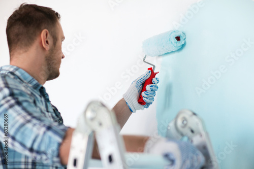 Photo: close up of male in gloves holding painting roller close up of male in gloves holding painting roller