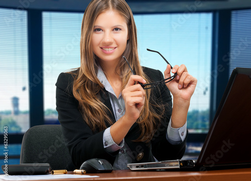 Photo: Smiling businesswoman holding her glasses Smiling businesswoman holding her glasses