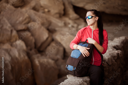 Photo: Young lady hiker with backpack in the cave Young lady hiker with backpack in the cave