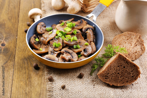 Photo: Delicious fried mushrooms in pan on table close-up Delicious fried mushrooms in pan on table close-up