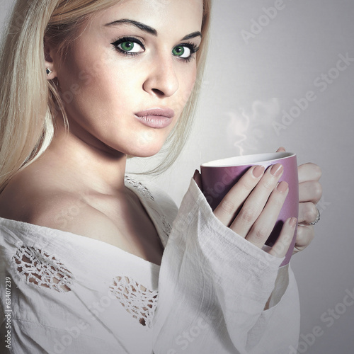 Photo: Beautiful blond woman drinking a Tea.Vapor Cup of Coffee.Hot Beautiful blond woman drinking a Tea.Vapor Cup of Coffee.Hot