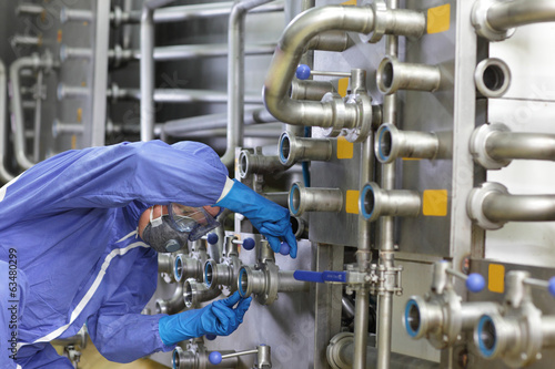 Photo: Technician in overalls maintaining technological system in plant Technician in overalls maintaining technological system in plant