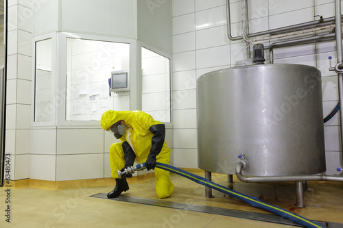 Photo: technician with large hose at industrial tank in plant technician with large hose at industrial tank in plant