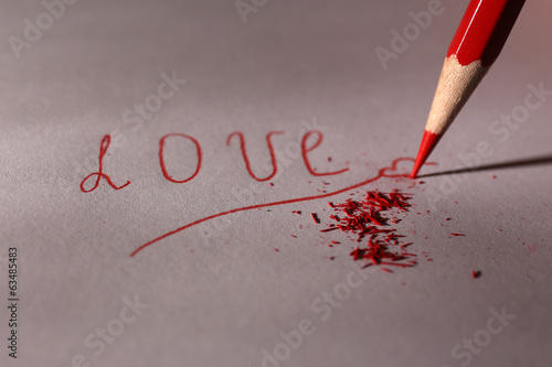 Photo: Word Love and breaking pencil on paper, close up Word Love and breaking pencil on paper, close up