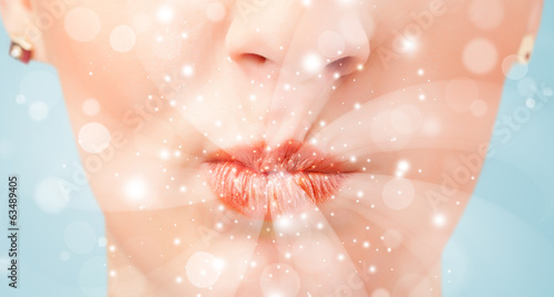 Photo: Pretty woman lips blowing abstract white lights Pretty woman lips blowing abstract white lights