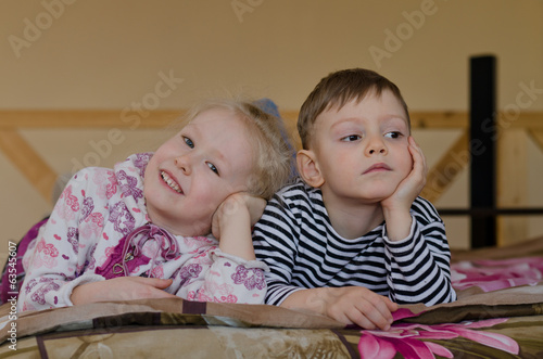 Photo: Young brother and sister lying on a bed together Young brother and sister lying on a bed together