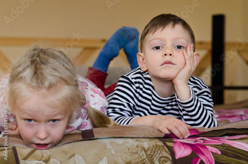 Photo: Young brother and sister lying on a bed together Young brother and sister lying on a bed together