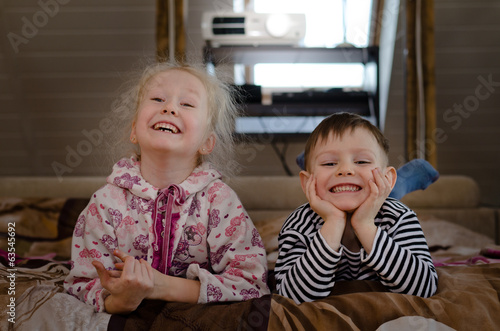 Photo: Young brother and sister lying on a bed together Young brother and sister lying on a bed together