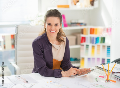 Photo: Happy fashion designer with tablet pc in office Happy fashion designer with tablet pc in office