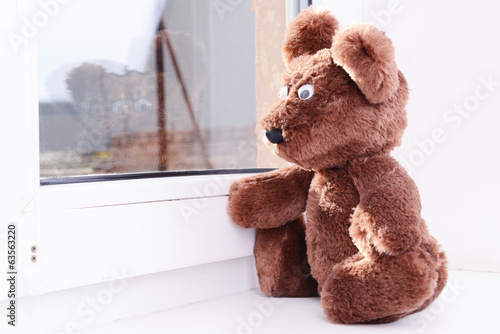 Photo: Toy-bear looking out window close-up Toy-bear looking out window close-up
