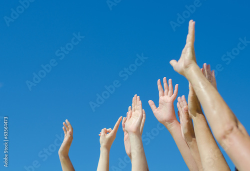 Photo: Many hands raised up against the blue sky. Many hands raised up against the blue sky.