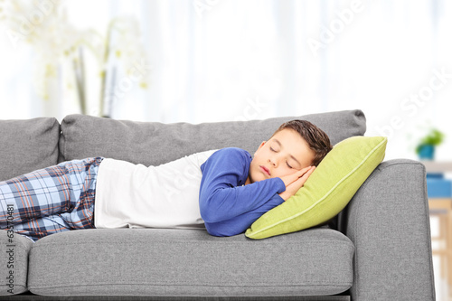 Photo: Cute little boy sleeping on sofa indoors Cute little boy sleeping on sofa indoors