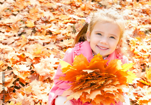 Photo: Autumn portrait of cute smiling little girl with maple leaves Autumn portrait of cute smiling little girl with maple leaves