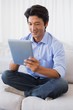 Happy man sitting on couch using tablet pc Happy man sitting on couch using tablet pc
