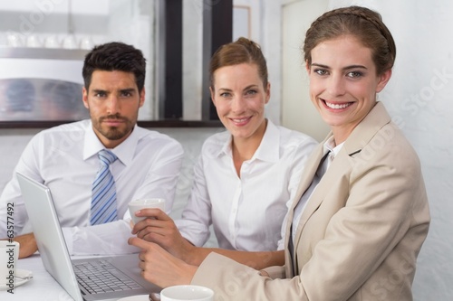 Photo: Business people using laptop together at office desk Business people using laptop together at office desk