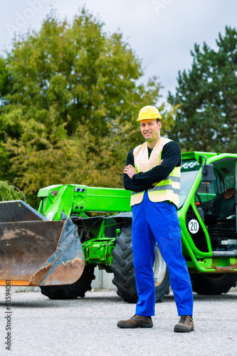 Photo: Bauarbeiter vor Baumaschine einer Baustelle Bauarbeiter vor Baumaschine einer Baustelle